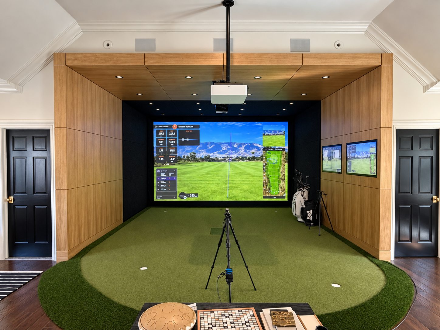 Custom wood-paneled TrackMan home simulator with curved putting green and integrated displays