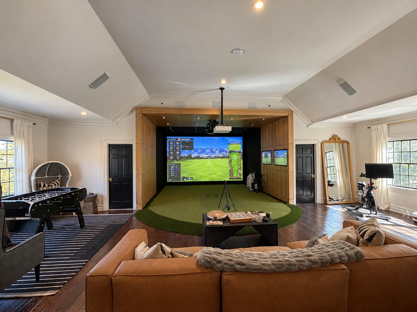 Completed TrackMan simulator opening onto a lounge with seating and a games table