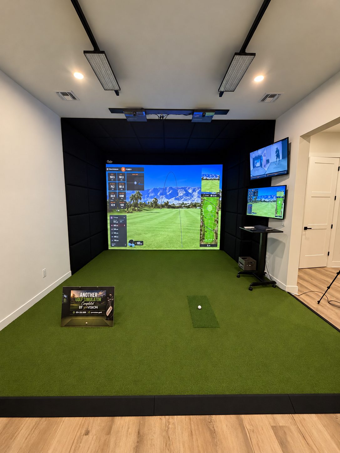 Front view of a TrackMan simulator enclosure with overhead equipment