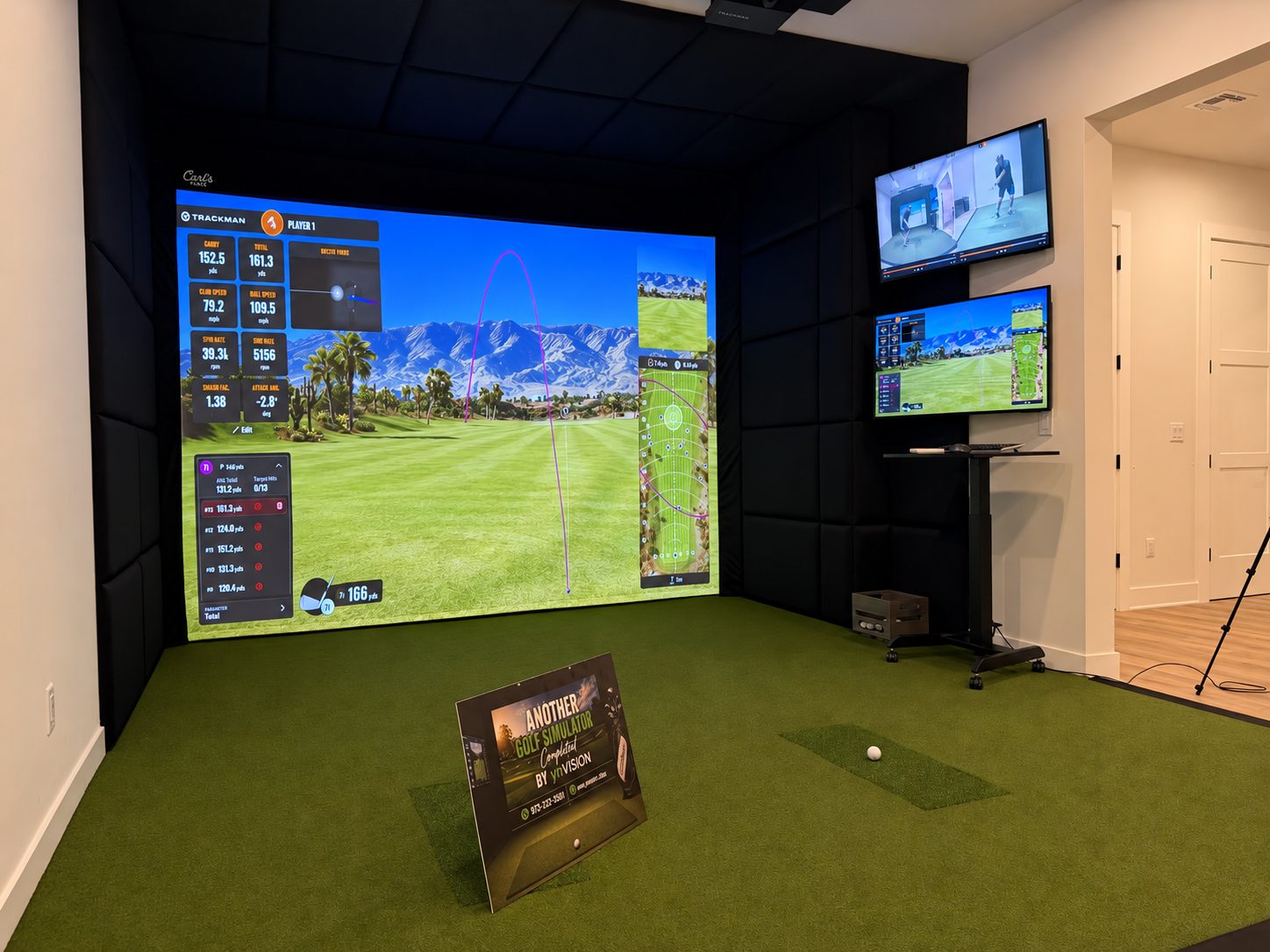 Angled view of a TrackMan simulator room with wall displays and impact screen