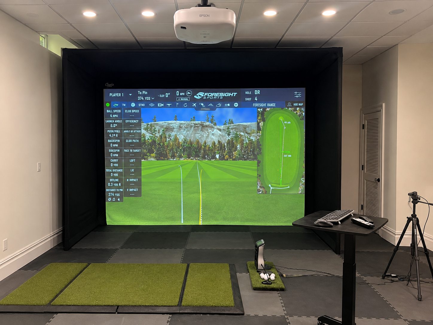 Foresight golf simulator enclosure with three hitting mats and a projected course