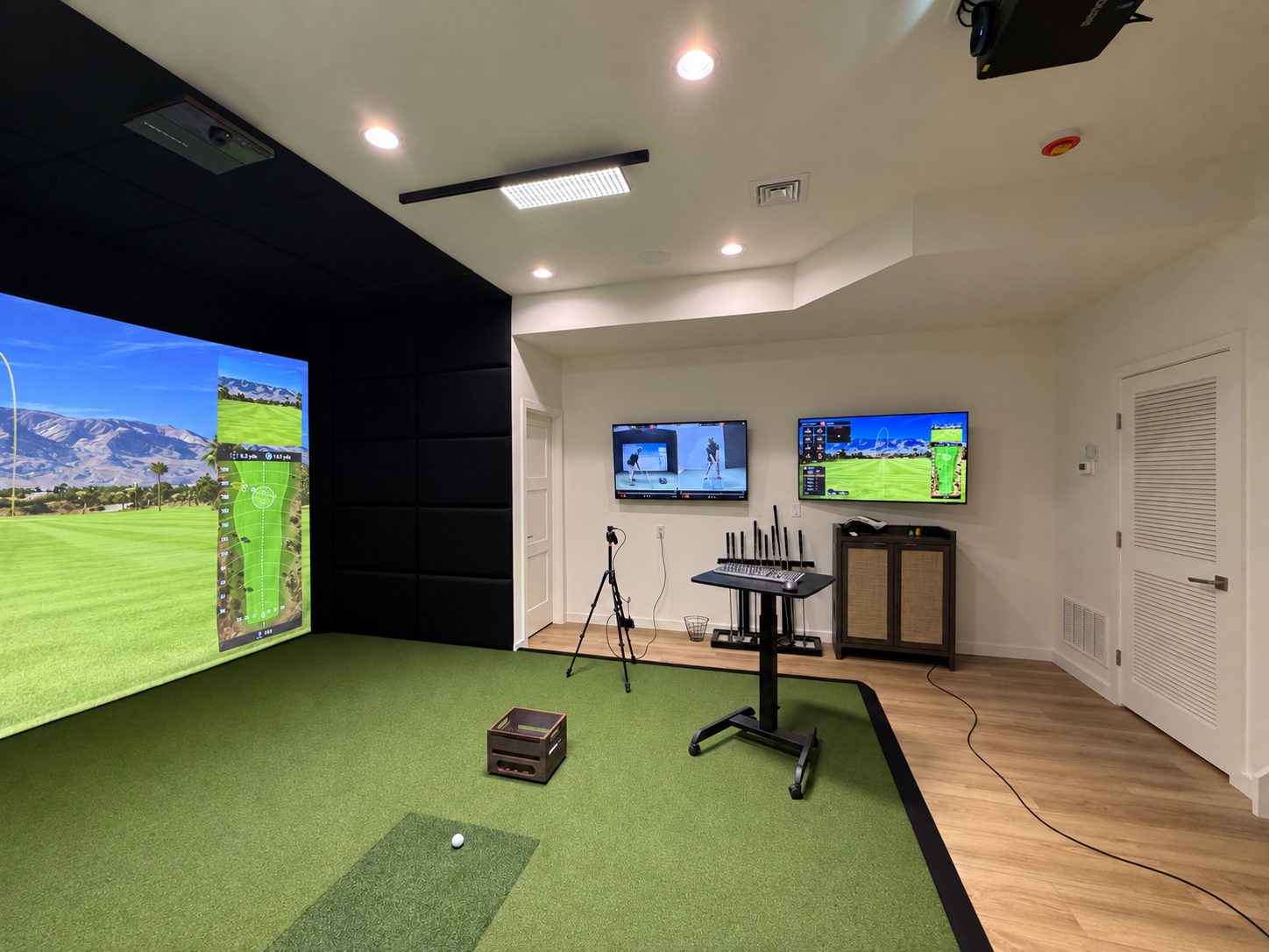 Side view of a padded TrackMan simulator with two wall displays