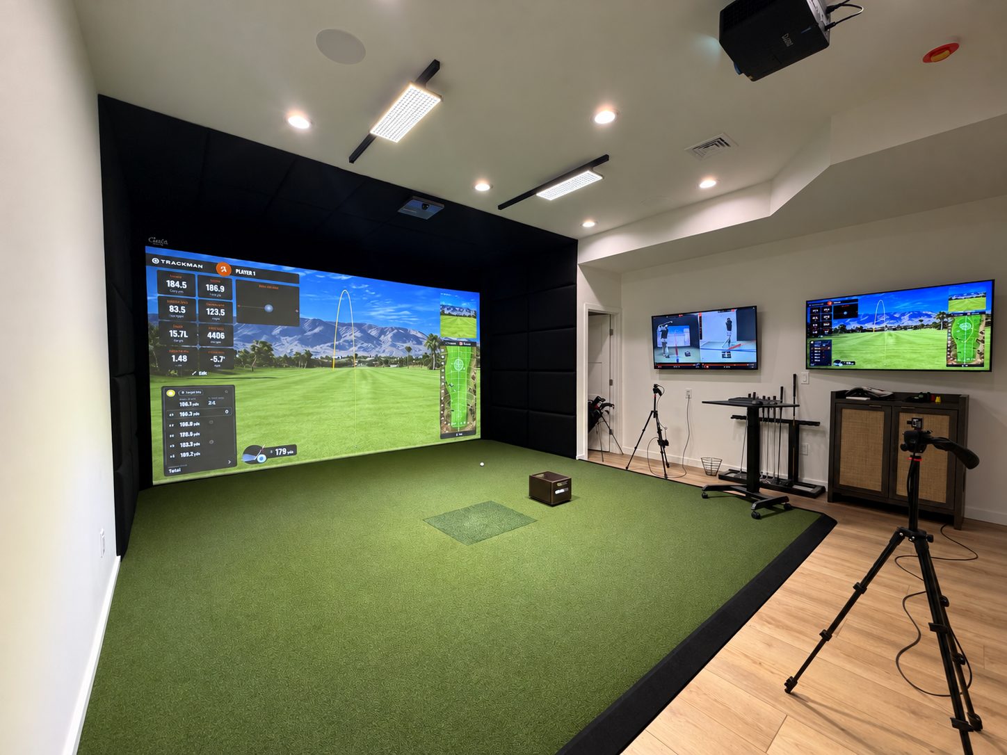 Finished padded TrackMan simulator room with projected course and turf hitting area
